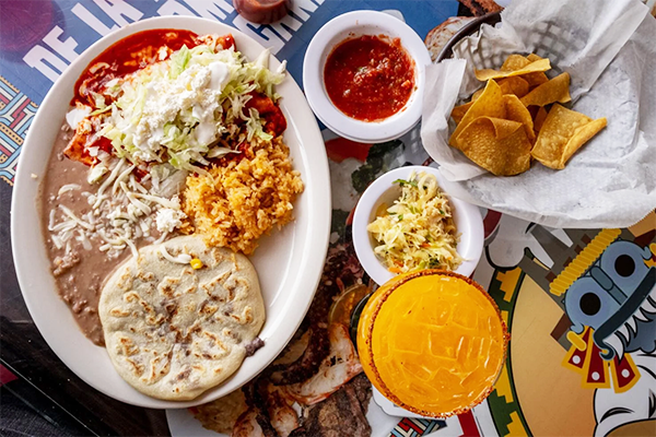 Plate of pupusa, rice, and beans next to a platter of chips and salsa and a cocktail | 1225 N Chase St, Athens, GA 30601